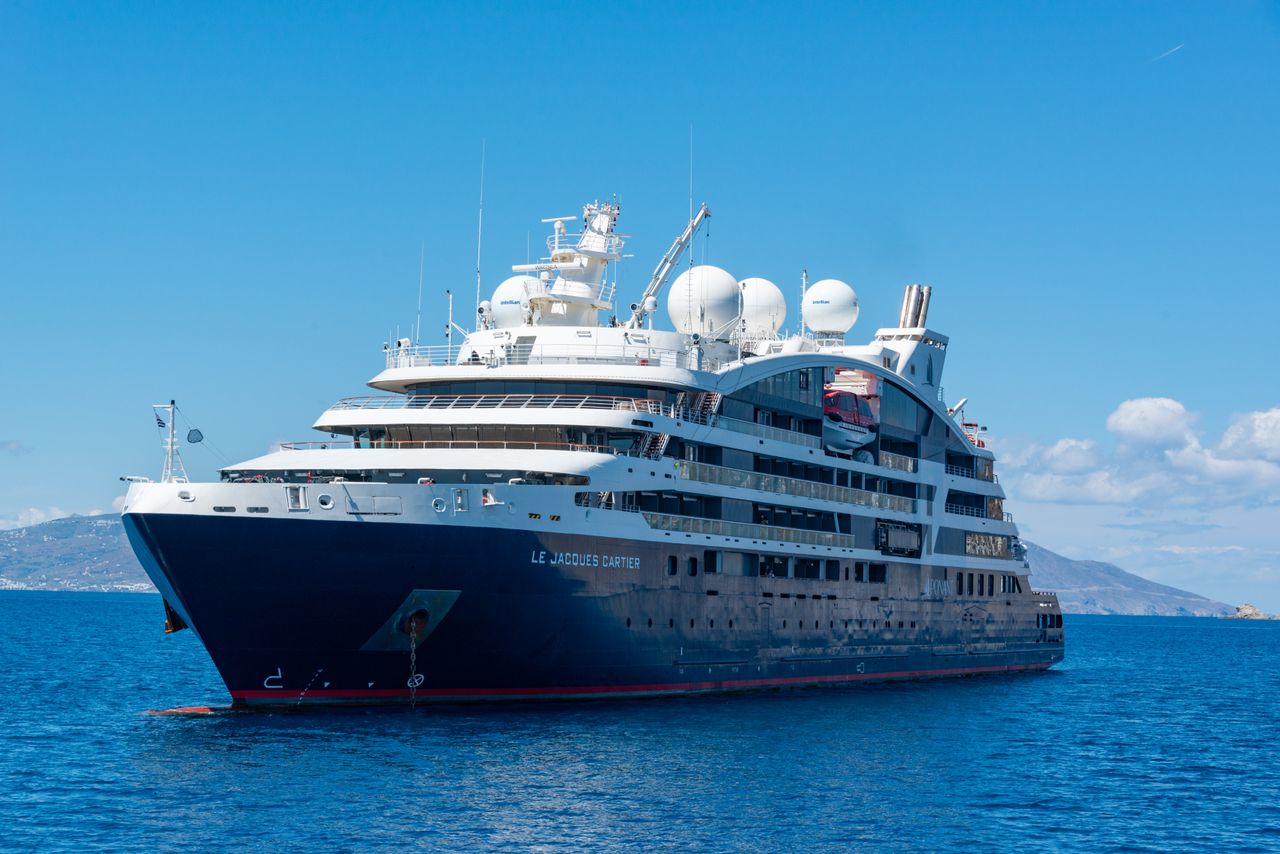 A luxury cruise ship sailing on open blue waters under a clear sky.